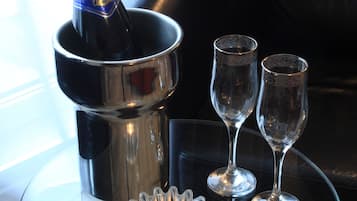 Ett glasbord med en champagneflaska, två vinglas och ett ljus.