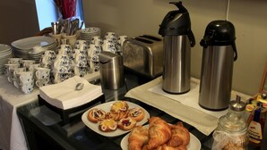 Un buffet de petit-déjeuner avec des assiettes de viennoiseries, un grille-pain et une machine à café.