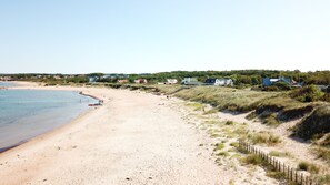 Une plage de sable avec des maisons et un ciel dégagé.