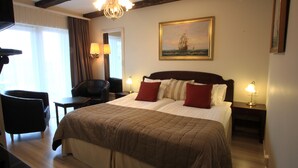 Une chambre d’hôtel avec un grand lit, un bureau, une chaise et un tableau au mur.
