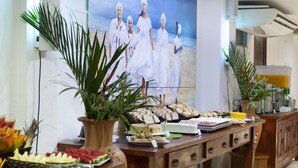 Un bufé con diversos alimentos y un cuadro grande de gente vestida de blanco en la pared.