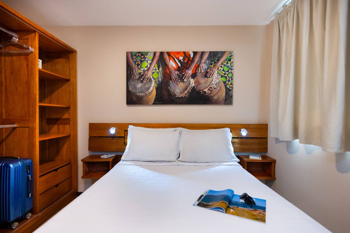 Une chambre d’hôtel avec un grand lit, une armoire en bois et un tableau au mur.