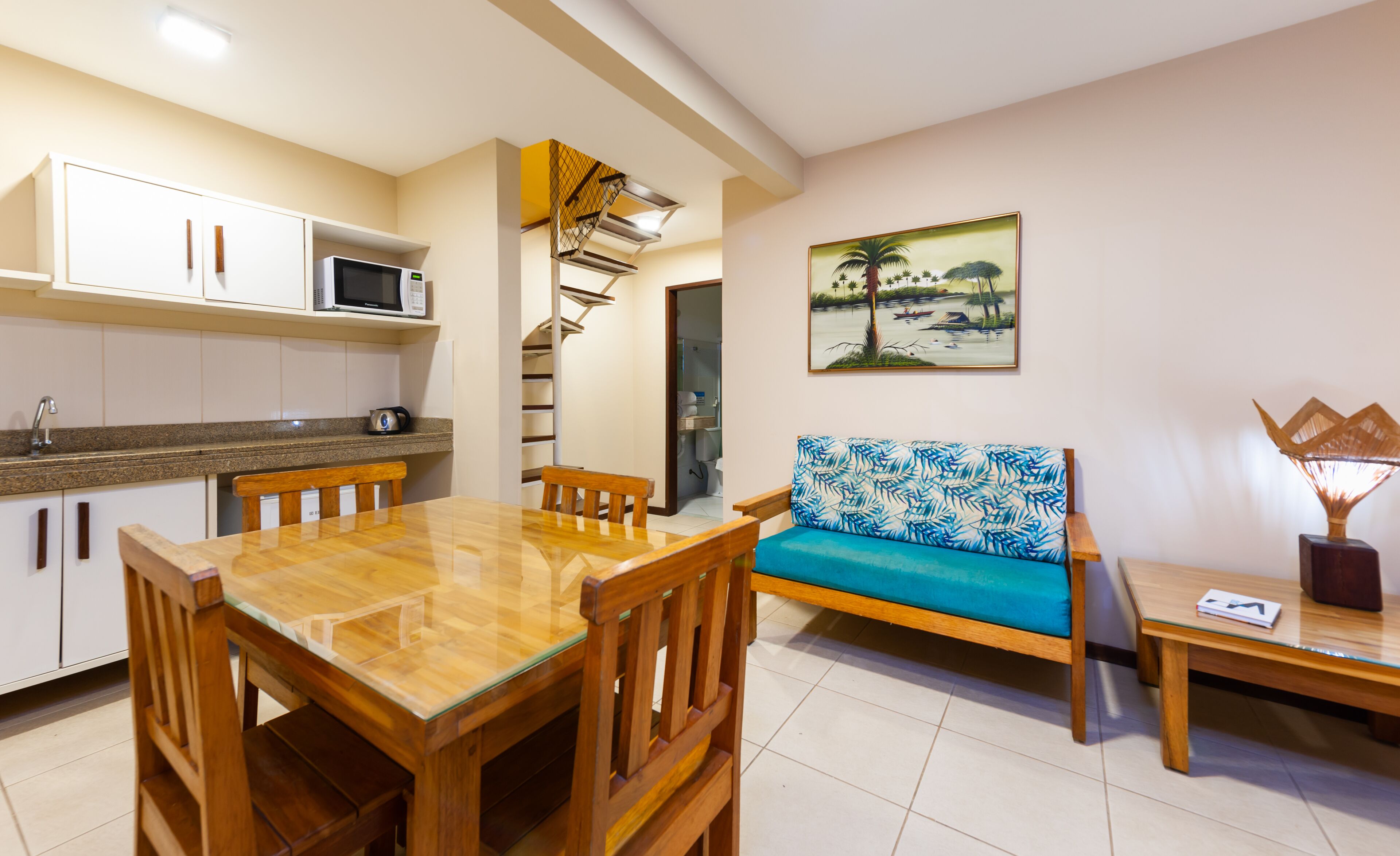A modern kitchen with white cabinets, a microwave, and a dining area with a wooden table and chairs.