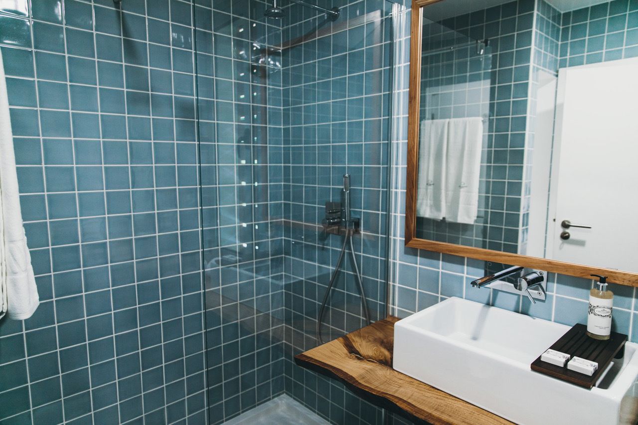 A bathroom with blue tiled walls, a wooden countertop, a white sink, and a mirror.