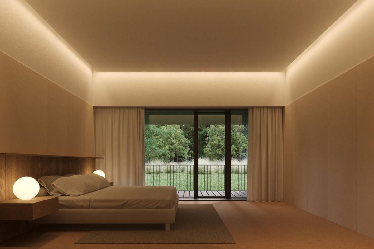 Een moderne slaapkamer met een bed, nachtkastje en uitzicht op een groen landschap door een grote schuifdeur.