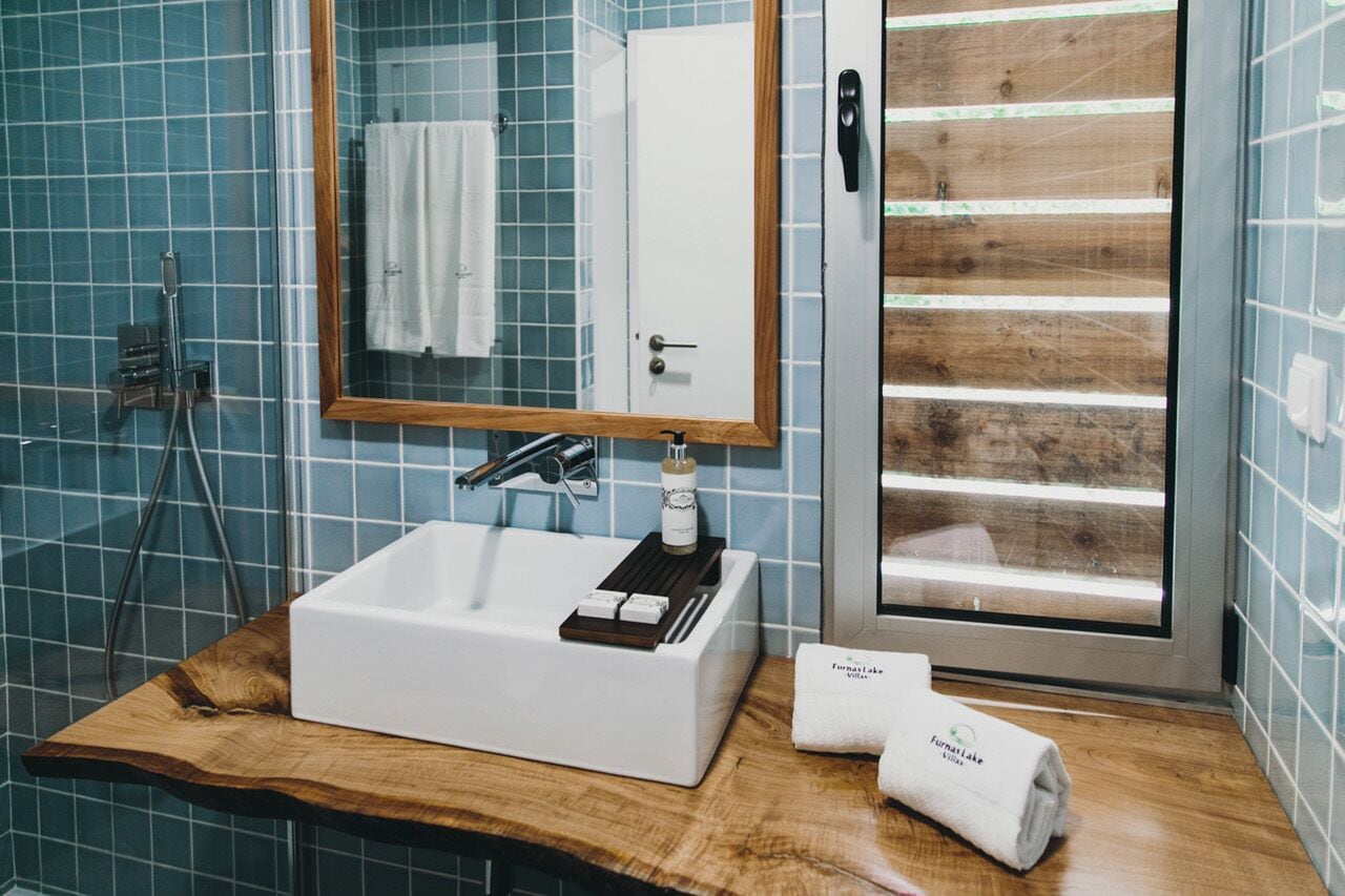 A bathroom with a white sink, a wooden vanity, a mirror, and a glass shower enclosure.