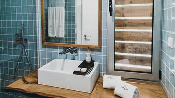 A bathroom with a white sink, a wooden vanity, a mirror, and a glass shower enclosure.