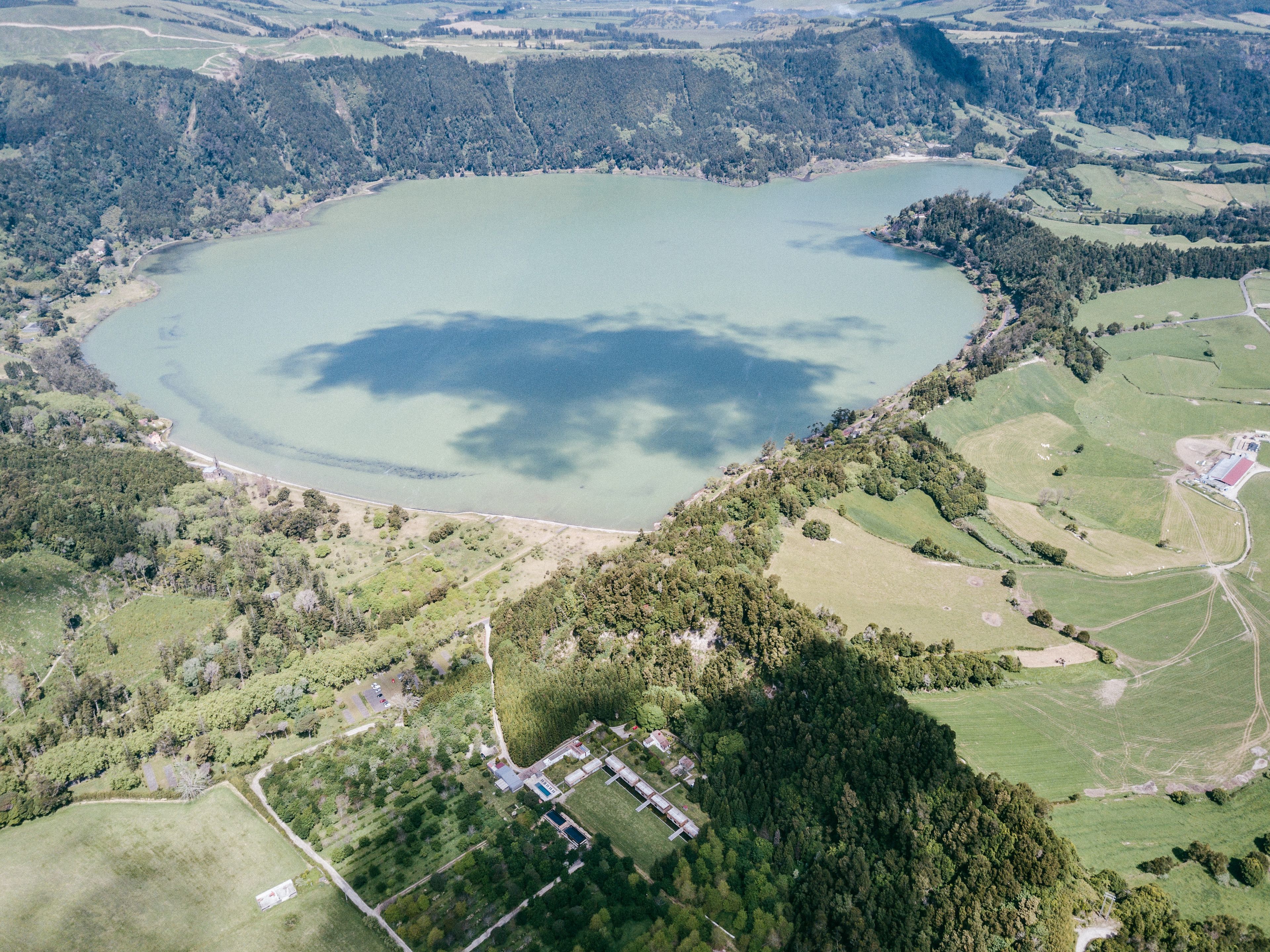 Vista aérea de un lago rodeado de colinas boscosas y campos.