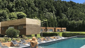 Zona de piscina con sillas de descanso y una persona sentada junto a la piscina.