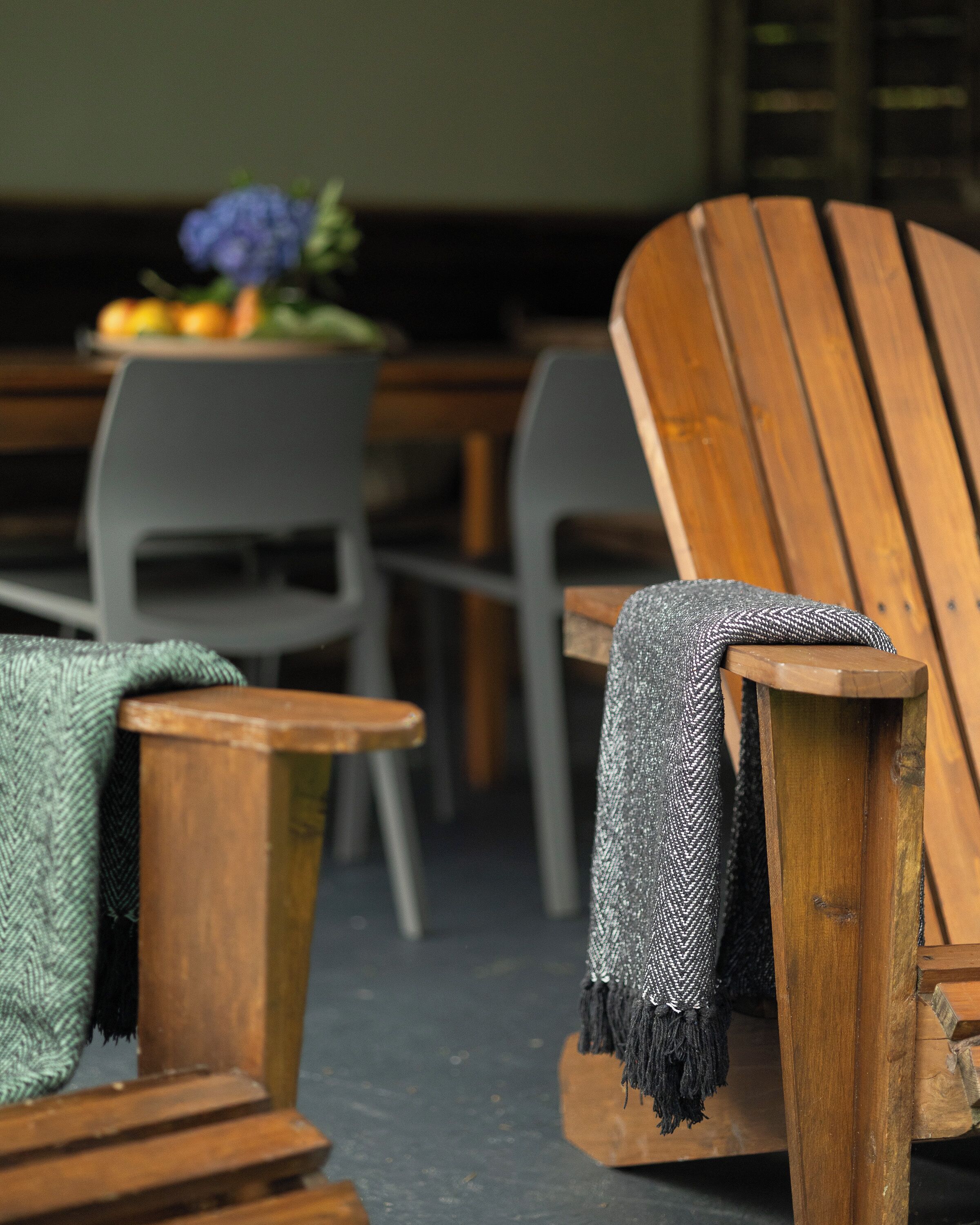 A wooden chair with a blanket, a small wooden stool, and a table with chairs in a room.