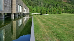 Un edificio moderno con una larga piscina reflectante y un césped cubierto de hierba.