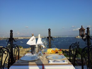 A table set for a meal with a view of the sea and a ship in the distance. - Mytra Hotel (Istanbul)