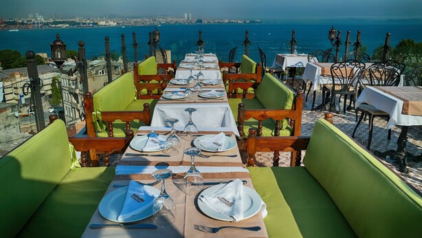 A dining area with tables set for two, overlooking a coastal cityscape. - Mytra Hotel (Istanbul)