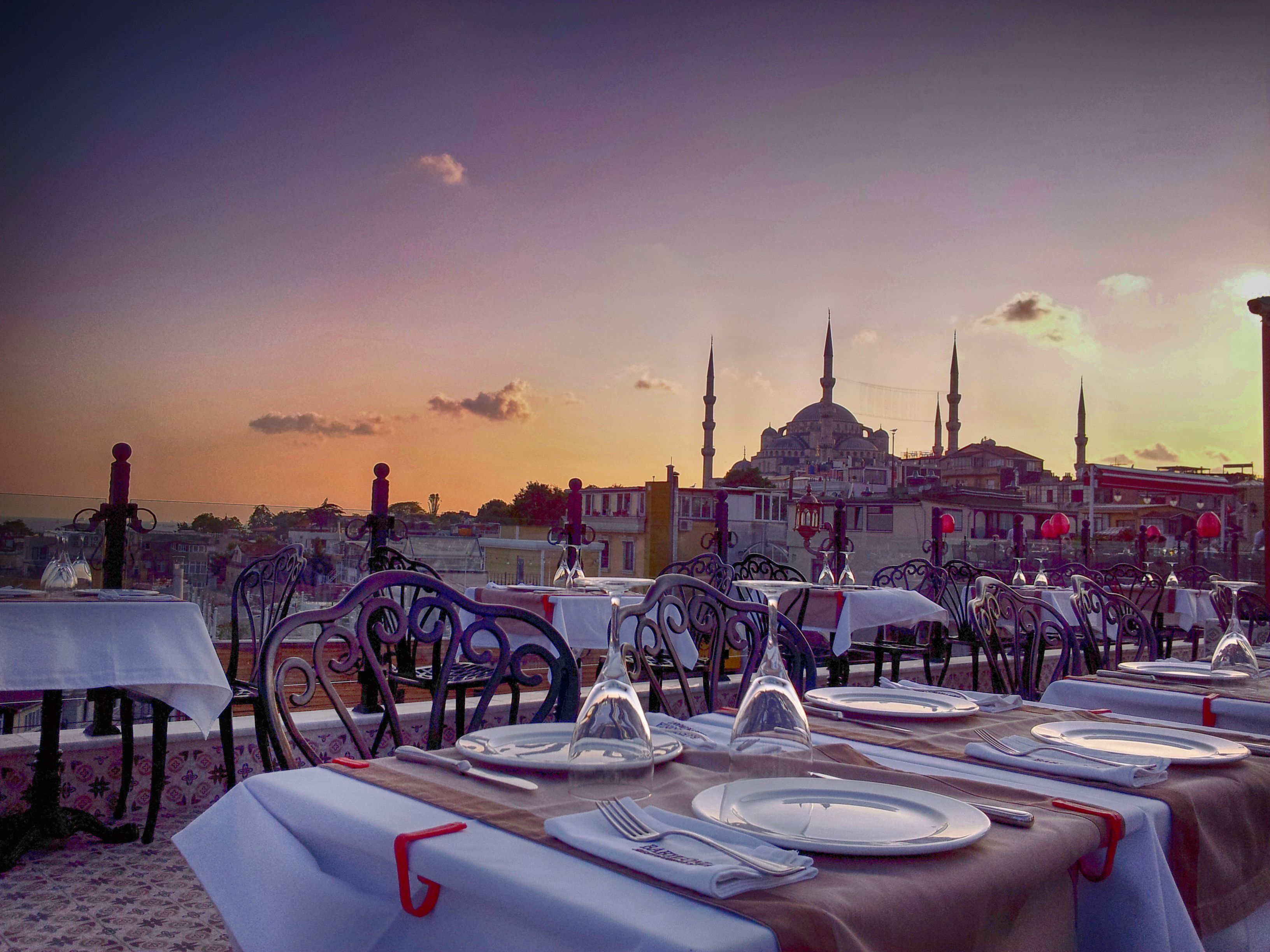 A table set for dining with a view of a historic building with multiple minarets in the background.