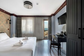 A hotel room with a large bed, a desk with a chair, a television, and a balcony with a view. - Mytra Hotel (Istanbul)