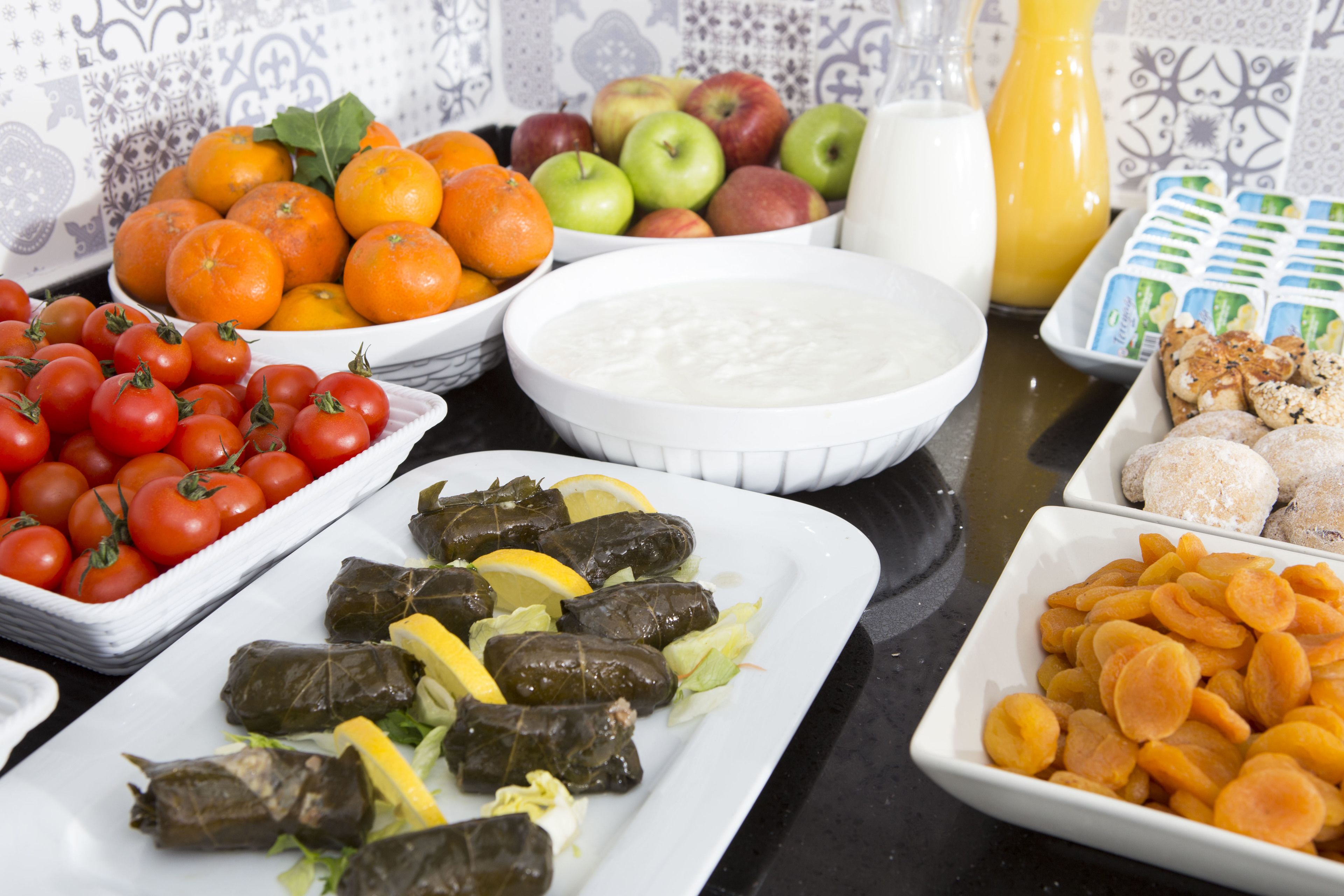 Una mesa con distintos alimentos, como tomates, limones y un tazón de yogur.