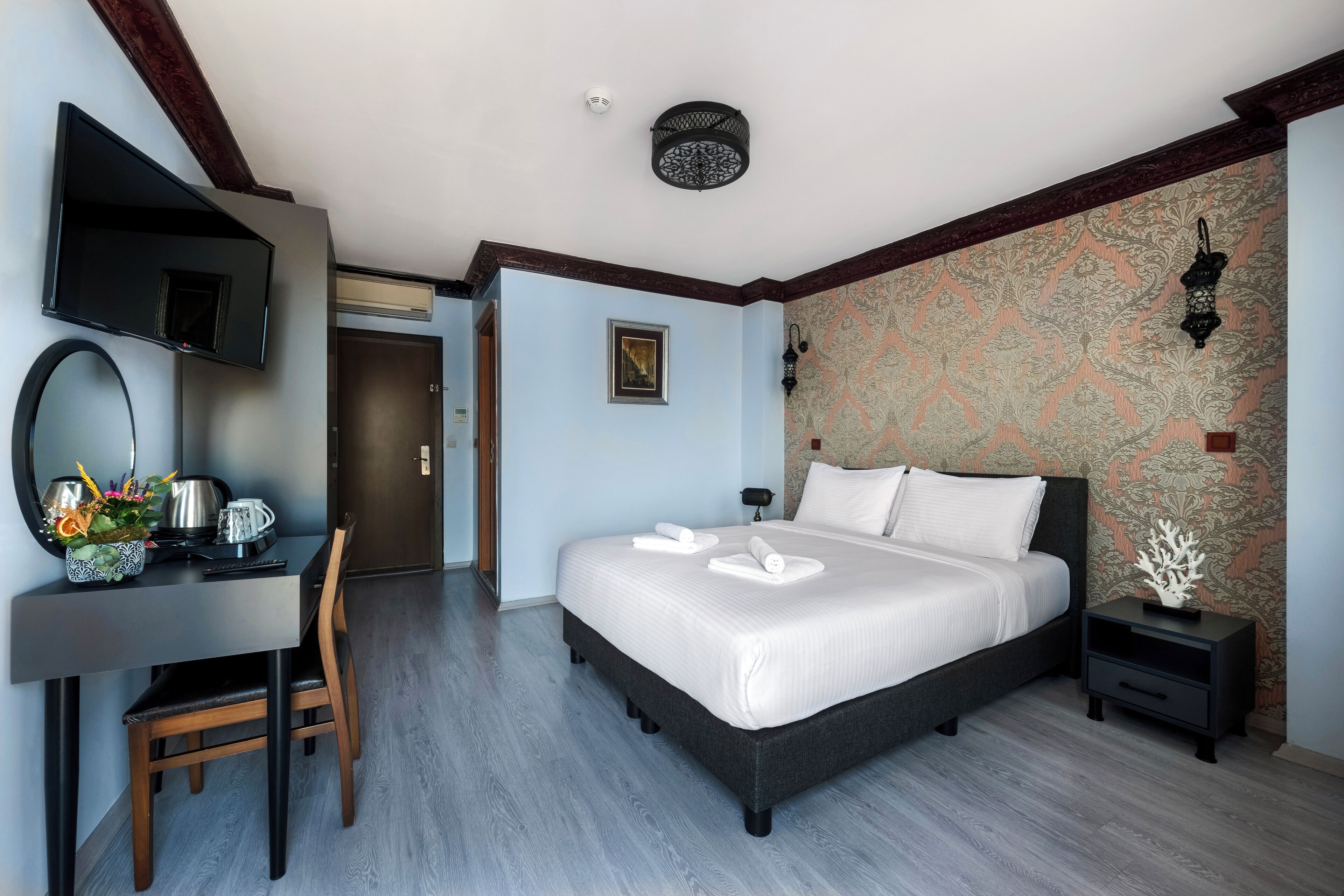 Una habitación de hotel moderna con una cama grande, un escritorio con silla, un televisor de pantalla plana y un adorno en la pared.