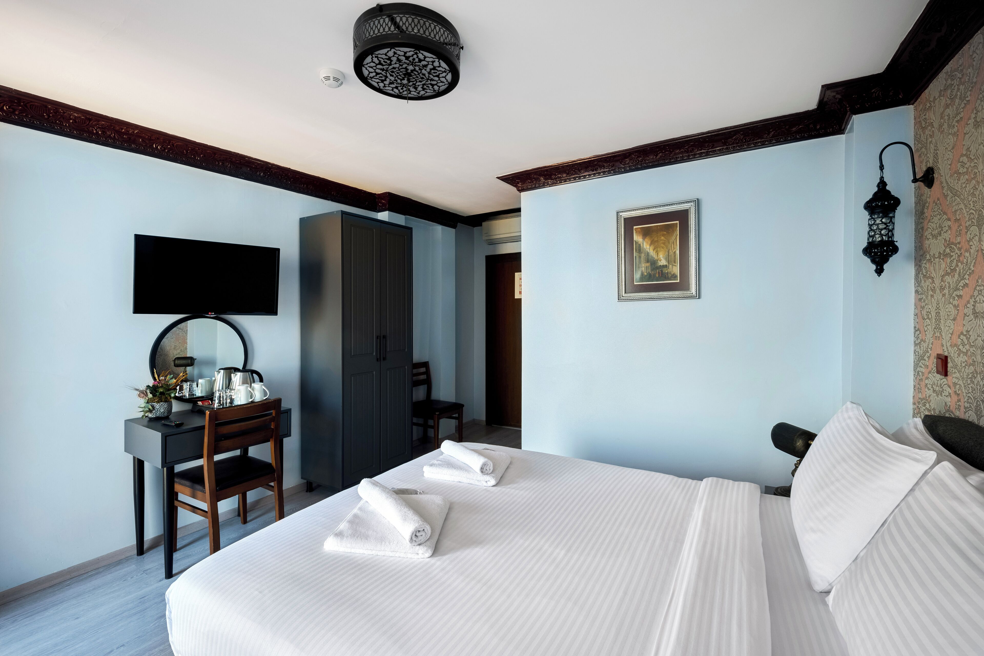 Ein Hotelzimmer mit einem Bett, einem Schreibtisch mit Stuhl, einem Flachbildfernseher und einem Kleiderschrank.