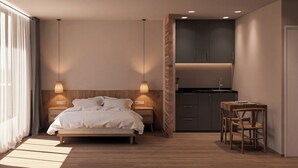 Un dormitorio moderno con cama, lámparas de noche, una mesita de madera y una zona de cocina integrada.