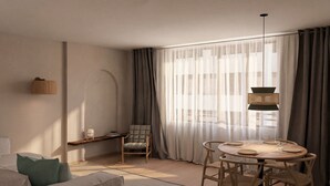 Una sala de estar moderna con un sofá, una mesa de comedor con sillas, una silla, una lámpara colgante y cortinas de gasa.