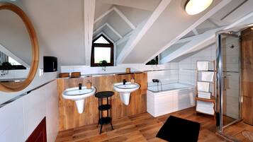 A modern bathroom with two sinks, a bathtub, and a shower.