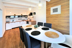 A modern kitchen with white cabinets, a wooden countertop, and hanging pendant lights.