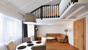 Una sala de estar moderna con una mesa de comedor, sofá y escalera.