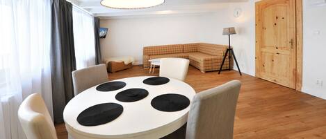 A dining area with a round table, chairs, and a hanging light fixture.