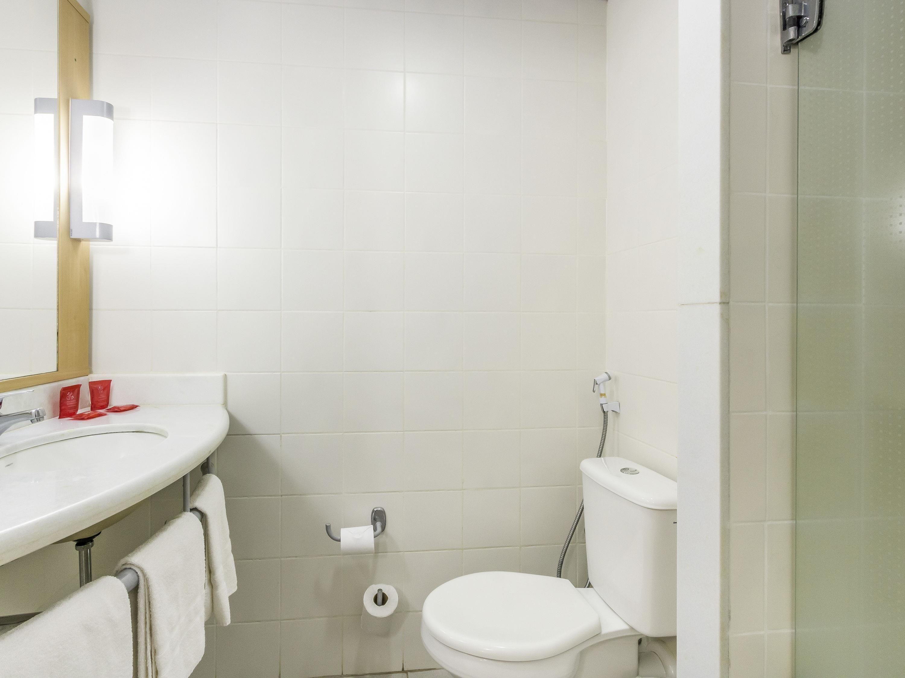 A bathroom with a white sink, toilet, and shower.