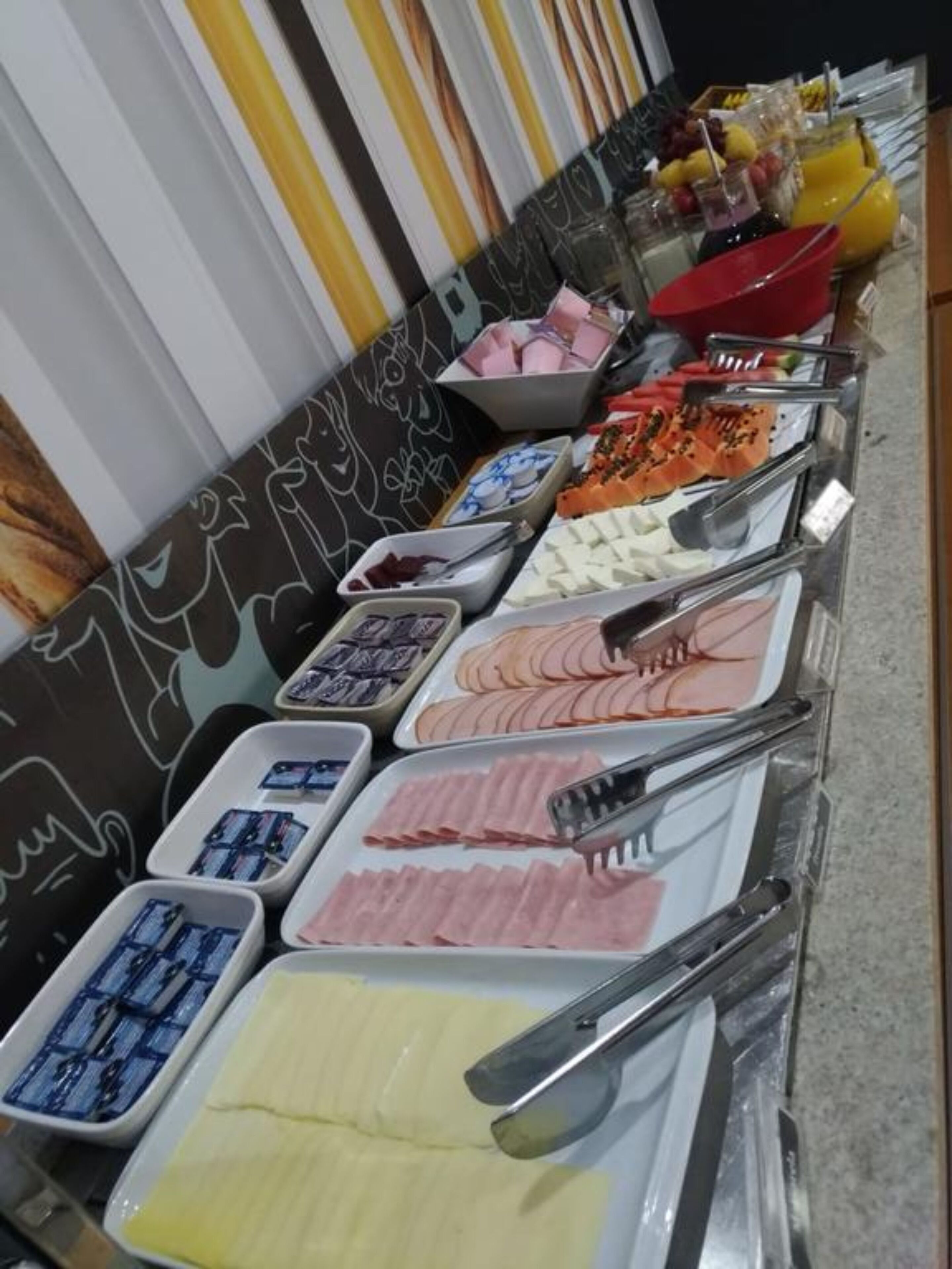 A buffet with various food options including meats, cheeses, and fruits.
