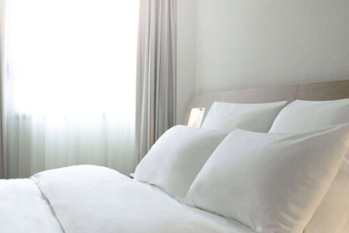 A hotel room with a bed, curtains, and a nightstand.