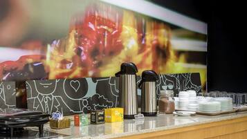 A hotel reception area with a counter displaying various amenities including thermoses, plates, and condiments.