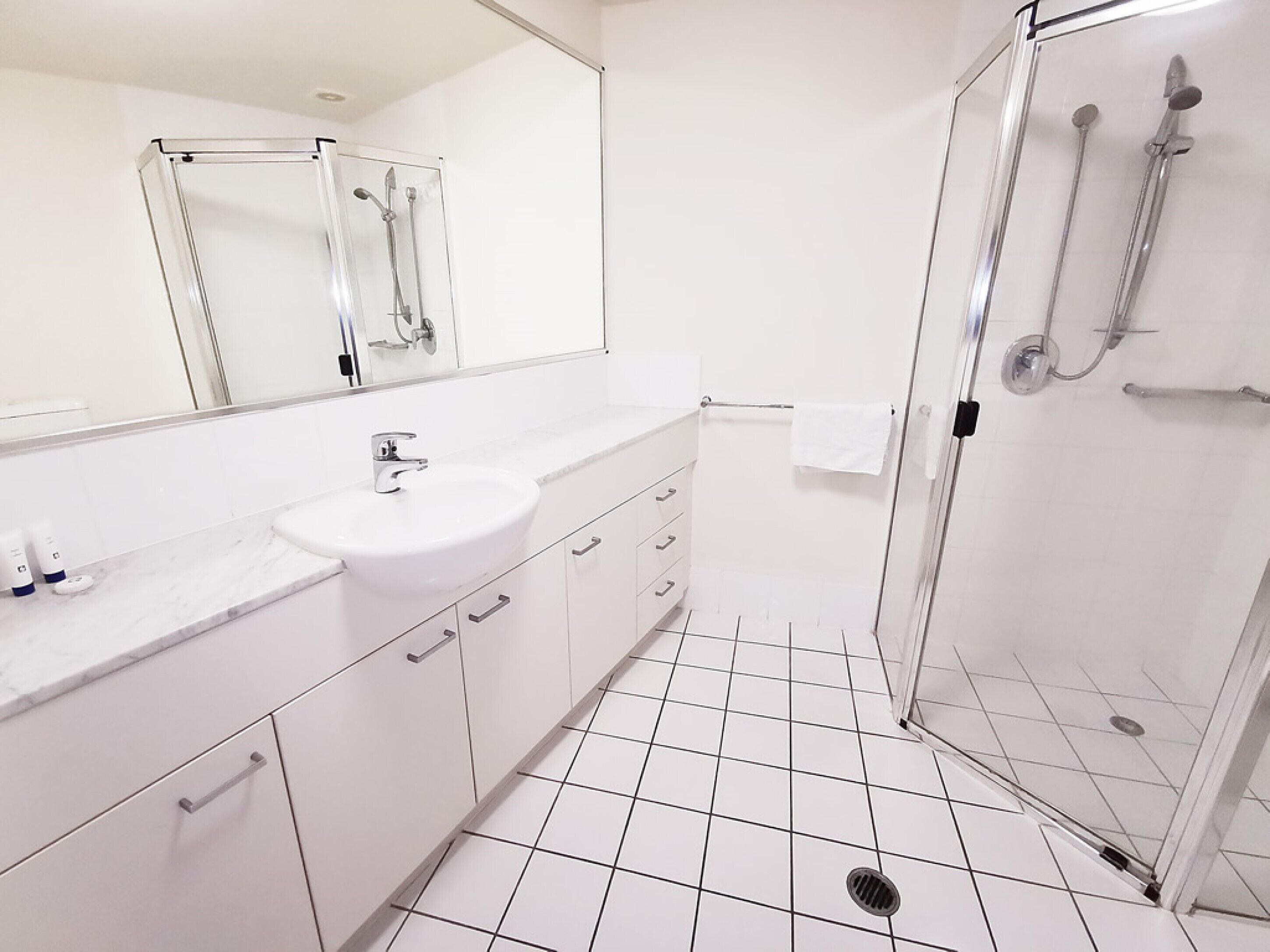Une salle de bain moderne avec un lavabo blanc, un miroir et une douche.