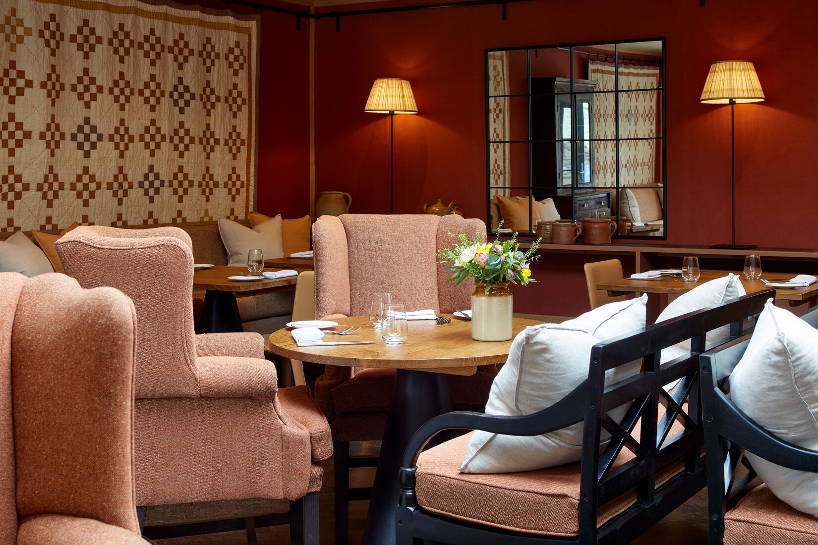 Een restaurant met ronde tafels, gestoffeerde stoelen en een bloevas.