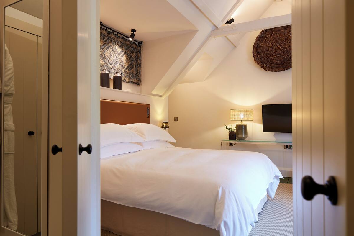 A bedroom with a bed, a bedside table with a lamp, a television, and a wall-mounted artwork.