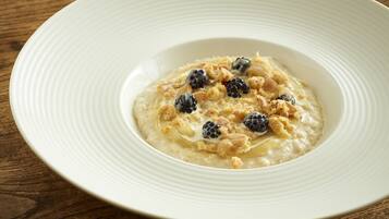 Un plato blanco con avena cubierta de arándanos y granola sobre una mesa de madera.