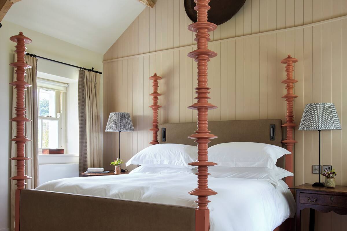 A bed with a wooden headboard, a nightstand, a lamp, and a wall-mounted clock.
