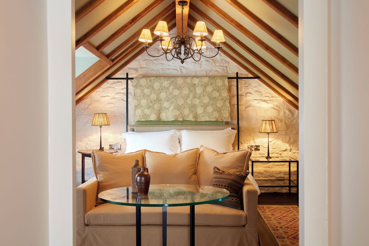 A cozy room with a glass table, a sofa, and a chandelier.