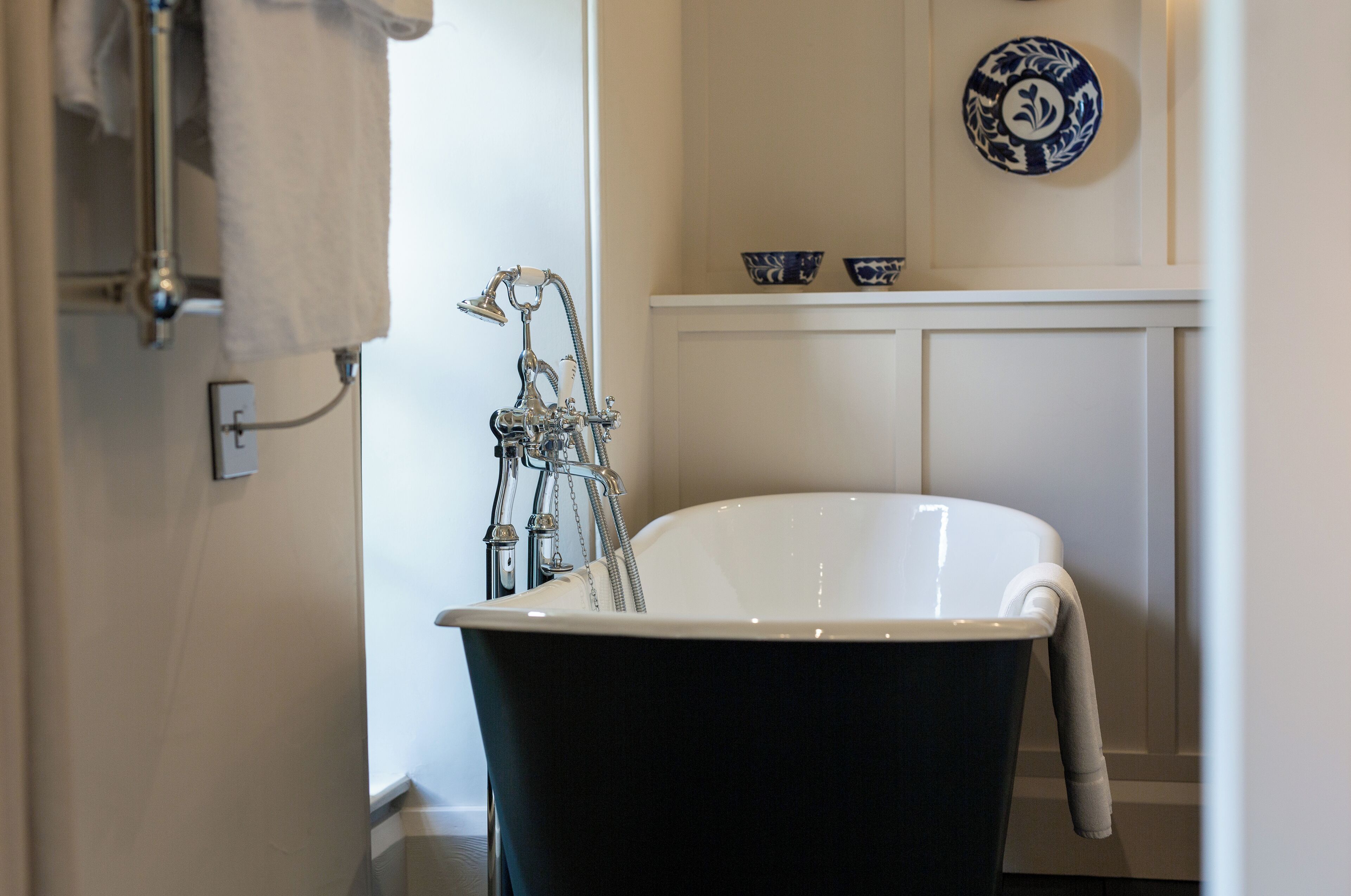 Une salle de bain avec une baignoire sur pieds, un porte-serviettes et des bols décoratifs accrochés au mur.