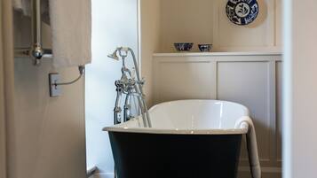 Une salle de bain avec une baignoire sur pieds, un porte-serviettes et des bols décoratifs accrochés au mur.