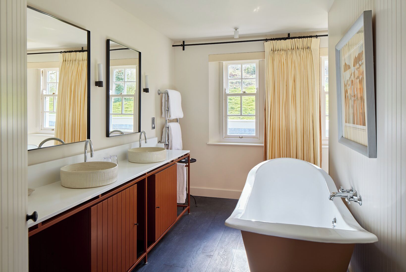 A bathroom with a freestanding bathtub, a double sink vanity, and a large mirror.