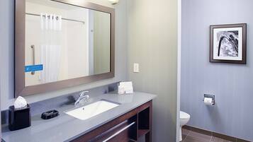 A bathroom with a large mirror, a sink, and a toilet.