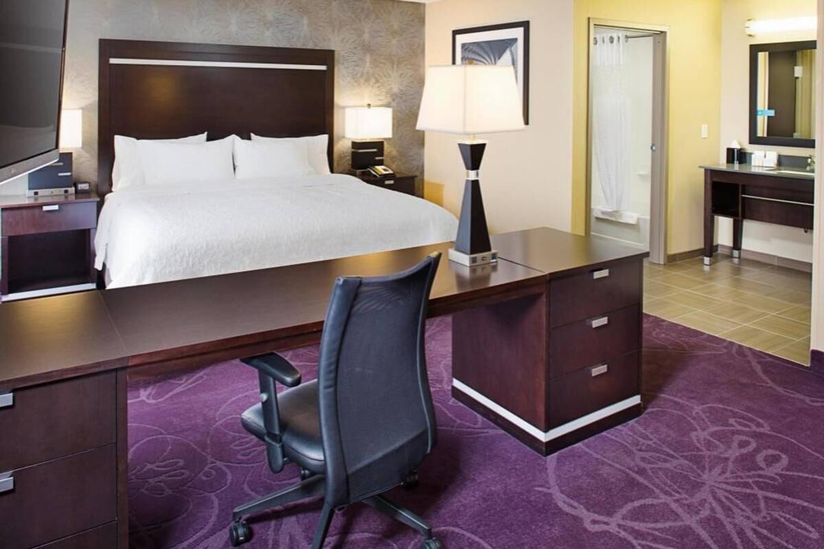 Une chambre d’hôtel comprenant un lit, un bureau, une chaise, une lampe de bureau, une table de chevet, une télévision et une salle de bain.