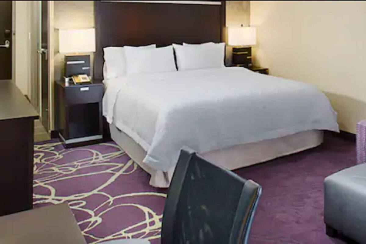 Une chambre d’hôtel avec un grand lit, une chaise, un bureau et une lampe.