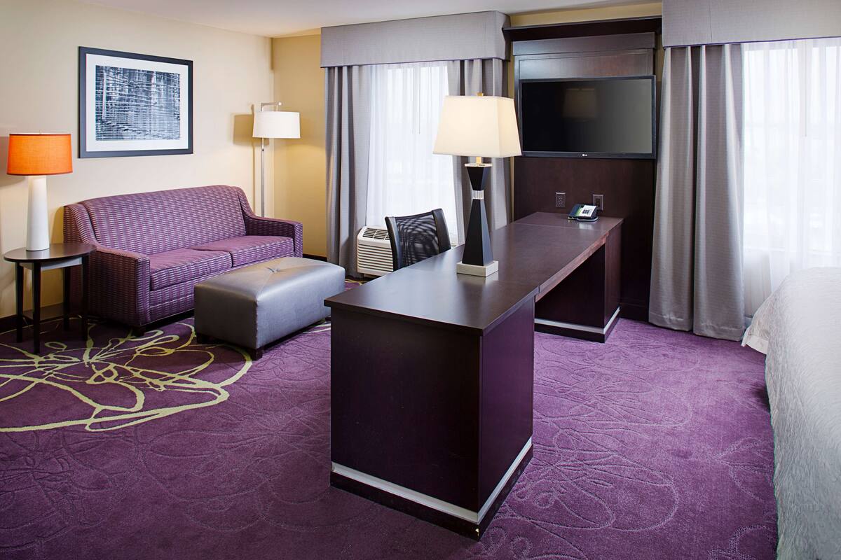 Une chambre d’hôtel avec un canapé, un bureau, une télévision et un lit.