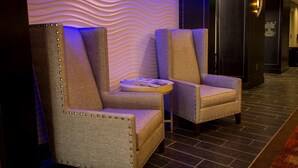 A lobby with two armchairs, a small table, and a wall with a wavy pattern.