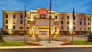 A Hampton Inn & Suites hotel with a modern facade, multiple floors, and a well-lit entrance.