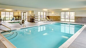 An indoor swimming pool with clear water, a lifeguard station, and lounge chairs.