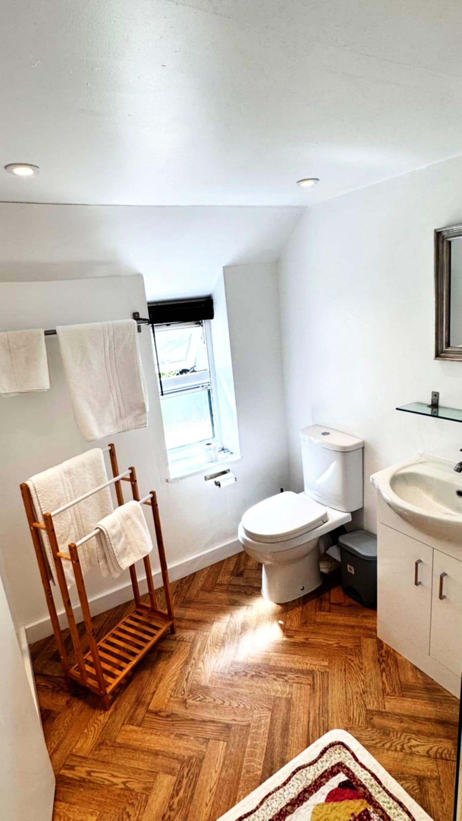 A small, compact bathroom with a toilet, sink, and towel rack.