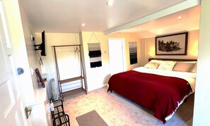 A bedroom with a bed, a door, a coat rack, and a wall-mounted artwork. - Bartles Lodge (Dereham)